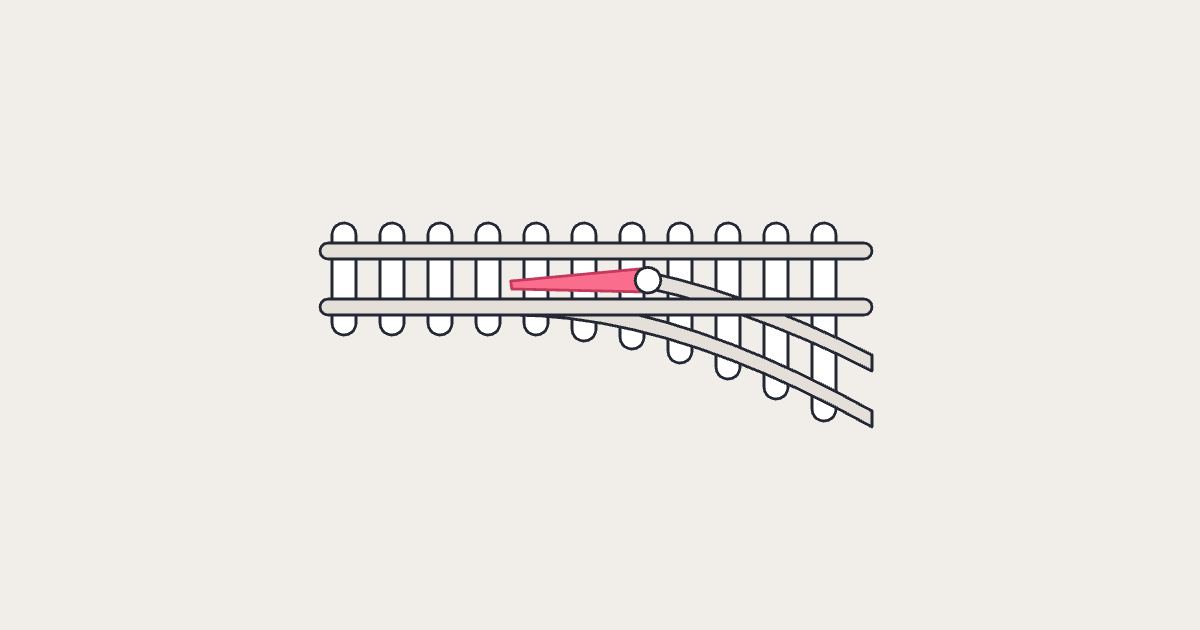 Railway points with the coral switch rail standing open, about to move across and send the track to the new line